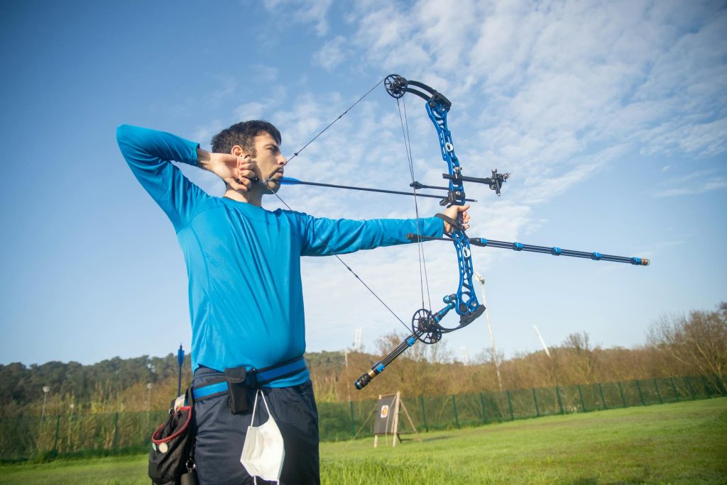 A Man in Blue Long Sleeves Using a Compound Bow